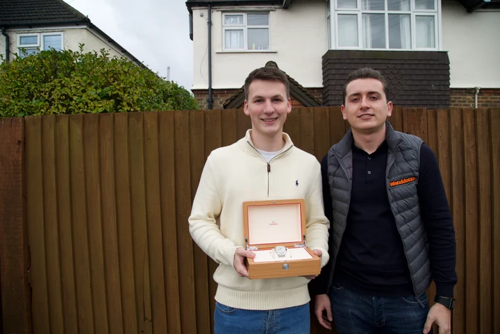 Harrison Gwinnett standing beside a Watchlotto winner holding an open watch box